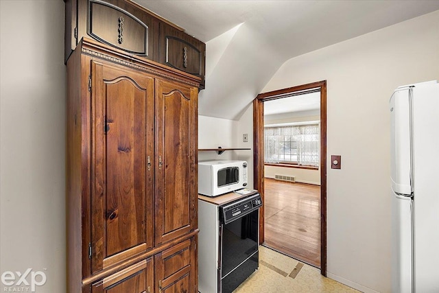 kitchen featuring white appliances and vaulted ceiling