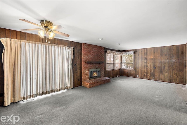 unfurnished living room with light carpet, ceiling fan, a brick fireplace, and wooden walls