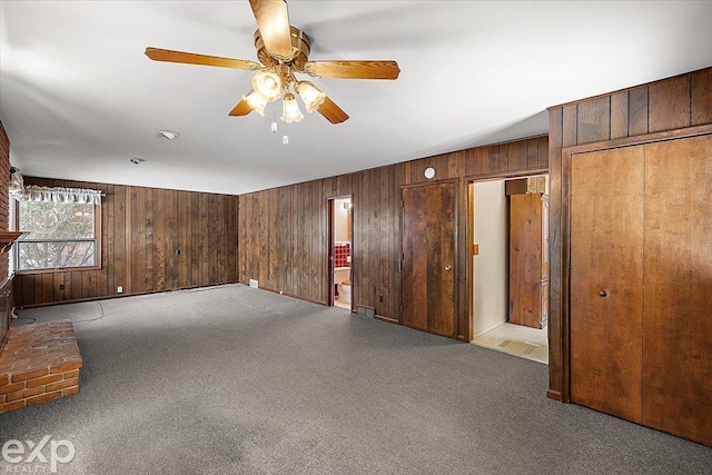 empty room with a fireplace, ceiling fan, and light colored carpet