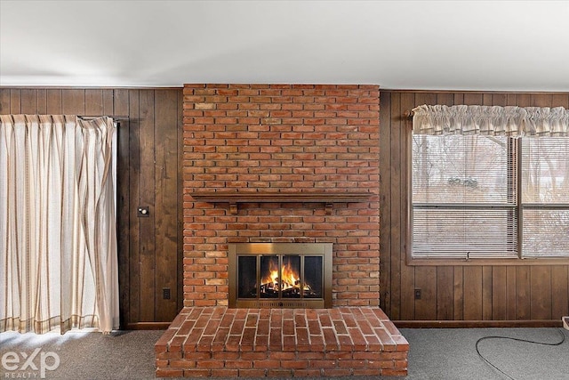 unfurnished living room featuring a fireplace, carpet flooring, and wooden walls