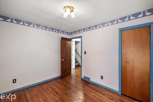 unfurnished bedroom featuring dark wood-type flooring and a closet