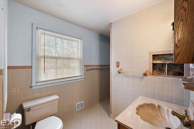 bathroom with toilet, vanity, tile walls, and tile patterned floors