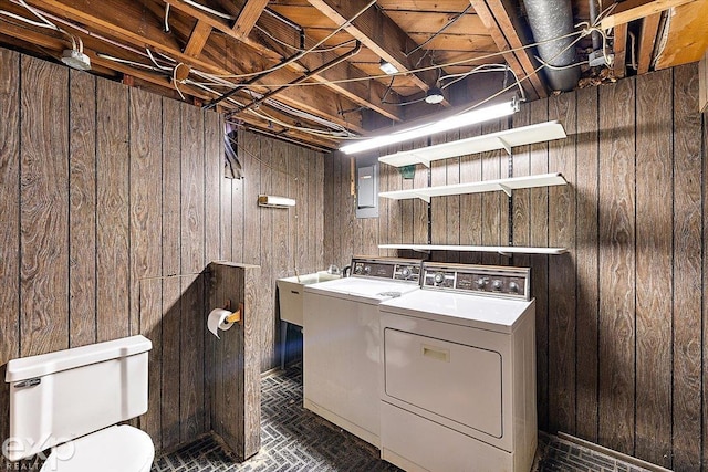 washroom featuring washer and dryer, sink, and wooden walls