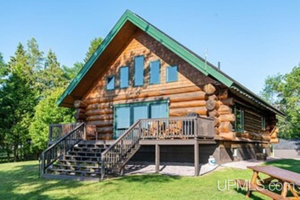 back of property with a wooden deck and a lawn