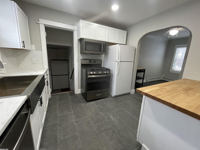 kitchen featuring wooden counters, white cabinetry, white refrigerator, tasteful backsplash, and gas range