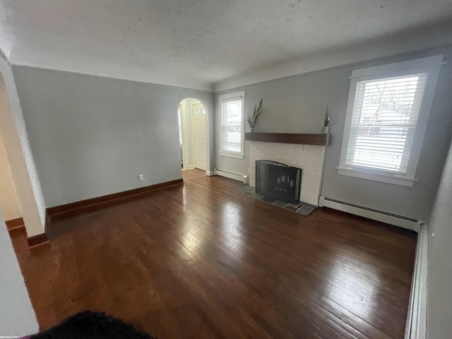 unfurnished living room featuring a baseboard heating unit, dark hardwood / wood-style flooring, and a tiled fireplace