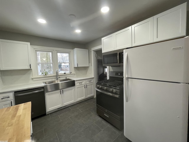 kitchen featuring white cabinetry, black dishwasher, white refrigerator, sink, and gas range