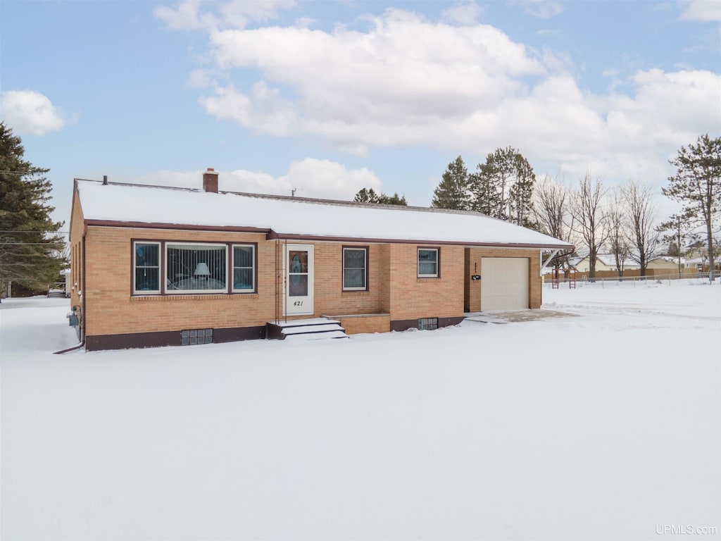 snow covered house featuring a garage