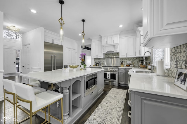 kitchen featuring sink, white cabinetry, built in appliances, and a kitchen island