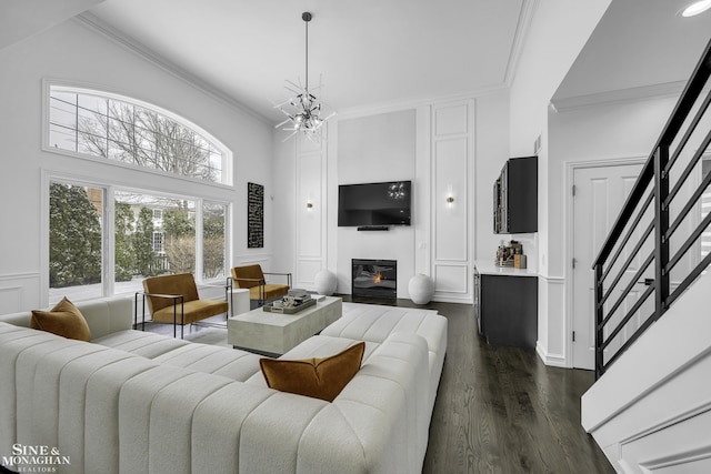 living room with dark hardwood / wood-style flooring, ornamental molding, and an inviting chandelier