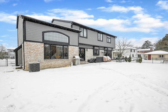 snow covered back of property featuring central AC unit