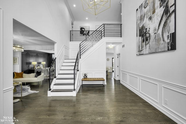 entryway with ornamental molding, dark hardwood / wood-style floors, and a notable chandelier