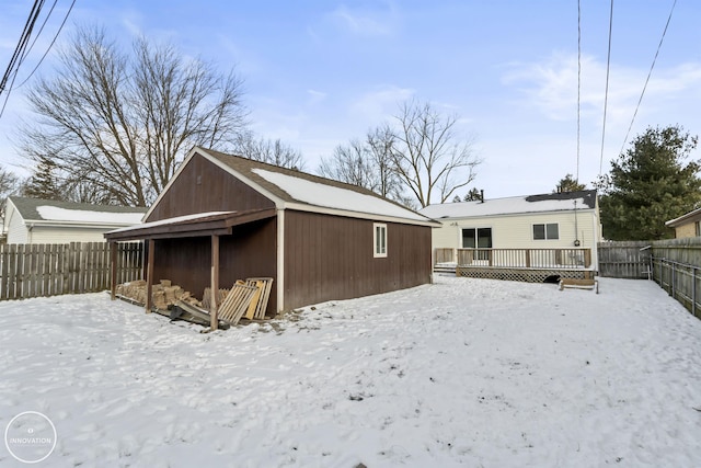 snow covered house with a wooden deck and an outbuilding