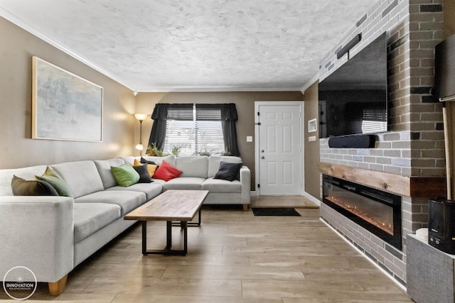 living room with a textured ceiling, a large fireplace, crown molding, and hardwood / wood-style flooring