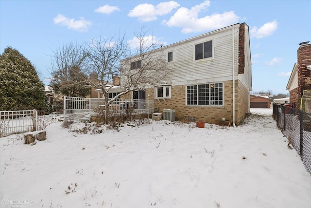 snow covered back of property featuring central air condition unit