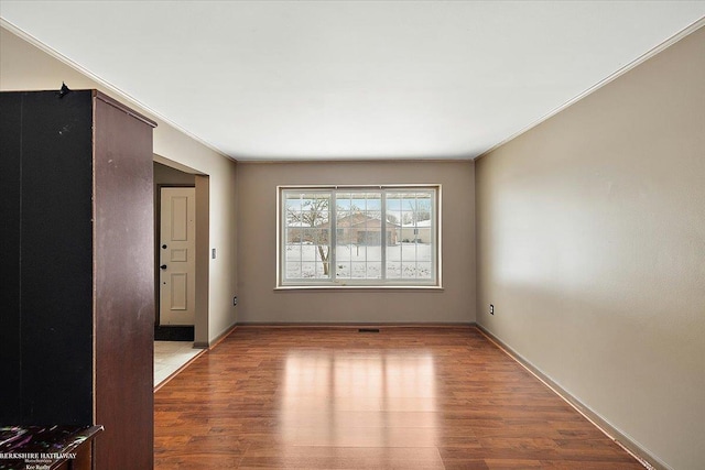 spare room with light wood-type flooring and crown molding