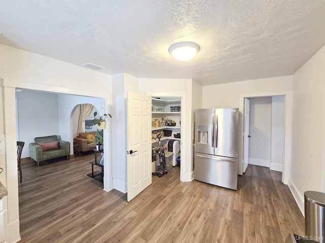 kitchen with a textured ceiling, wood-type flooring, and stainless steel fridge