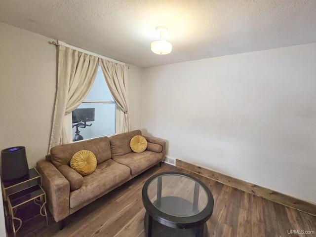 living room featuring a textured ceiling and dark hardwood / wood-style floors