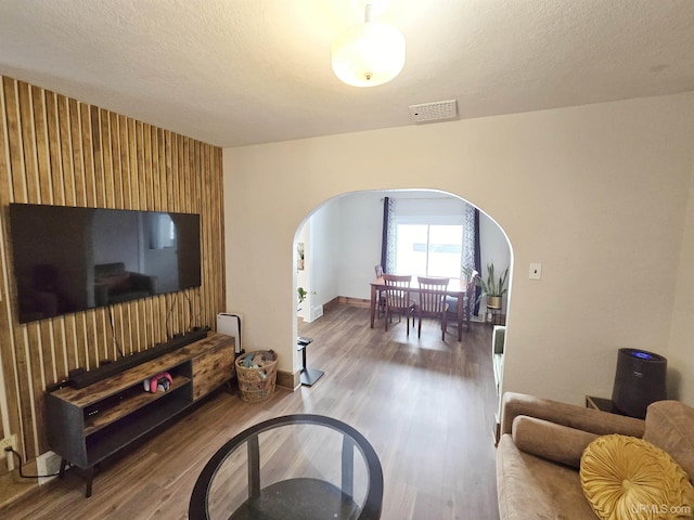 living room featuring wooden walls, a textured ceiling, and hardwood / wood-style flooring