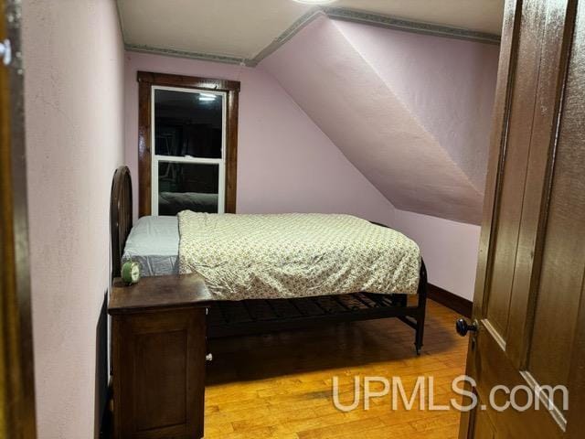 bedroom featuring light hardwood / wood-style floors and lofted ceiling