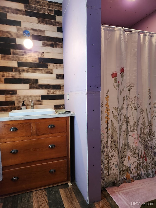 bathroom with sink, wood-type flooring, and wood walls