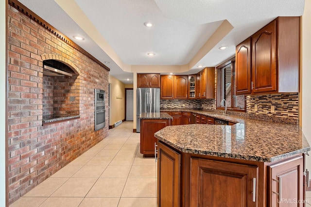 kitchen with a kitchen island, stainless steel appliances, dark stone counters, tasteful backsplash, and light tile patterned floors