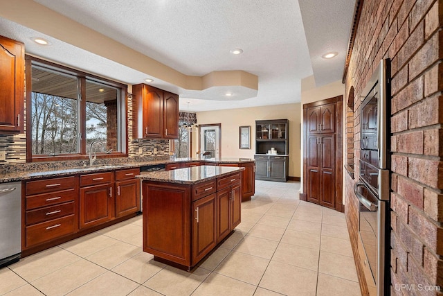 kitchen with stainless steel dishwasher, decorative backsplash, dark stone counters, and a center island