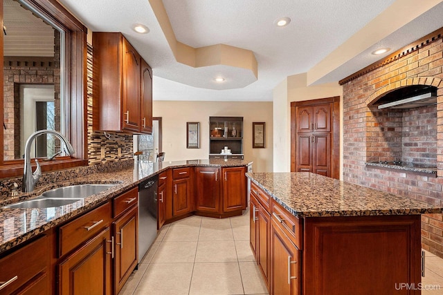 kitchen featuring dishwashing machine, dark stone counters, sink, and a center island