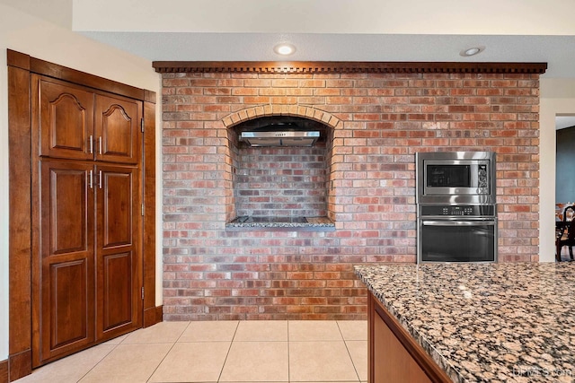 kitchen featuring light tile patterned floors, appliances with stainless steel finishes, and dark stone counters