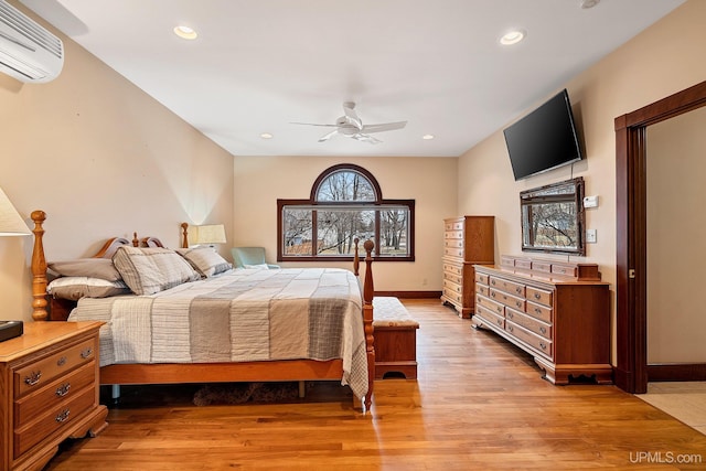 bedroom with ceiling fan, light hardwood / wood-style flooring, and a wall mounted air conditioner