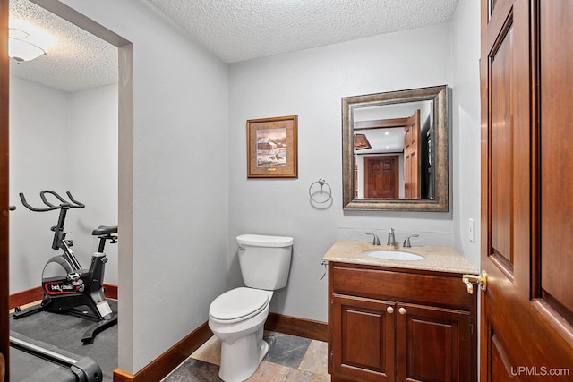 bathroom featuring a textured ceiling, toilet, and vanity