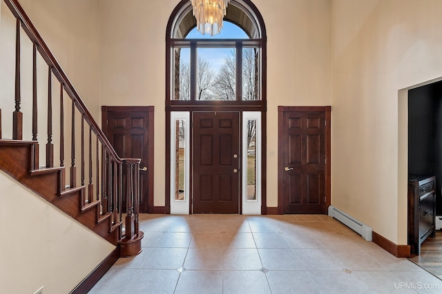 entrance foyer featuring a baseboard heating unit, a high ceiling, and a chandelier