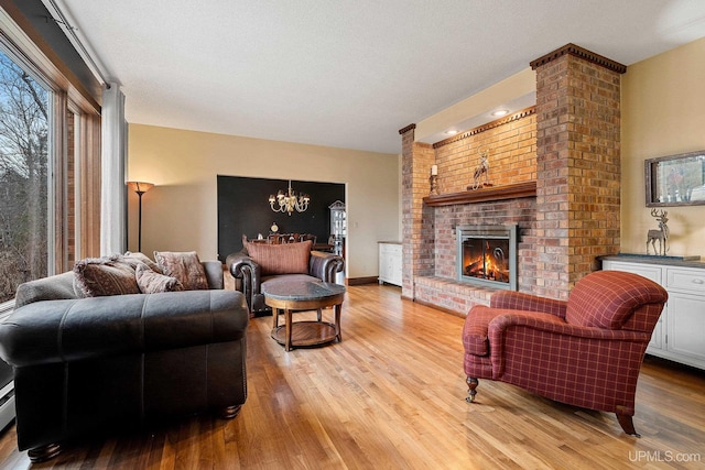 living room featuring a textured ceiling, an inviting chandelier, light hardwood / wood-style floors, and a fireplace