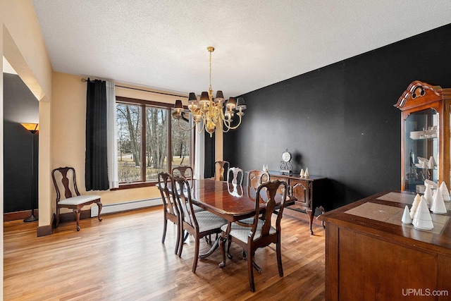 dining area featuring a textured ceiling, an inviting chandelier, and light hardwood / wood-style floors