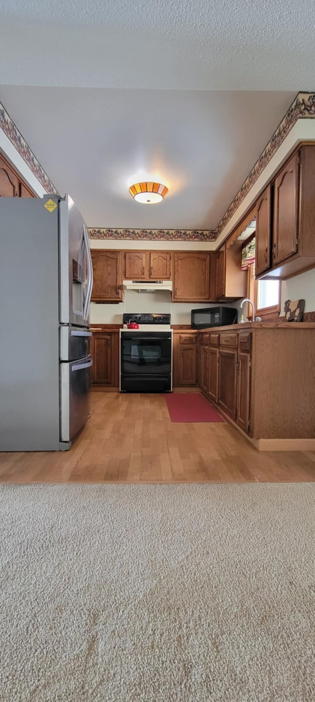 kitchen with electric stove, stainless steel fridge, a textured ceiling, and light hardwood / wood-style flooring