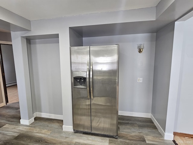 kitchen with dark wood-type flooring, a baseboard radiator, and stainless steel fridge