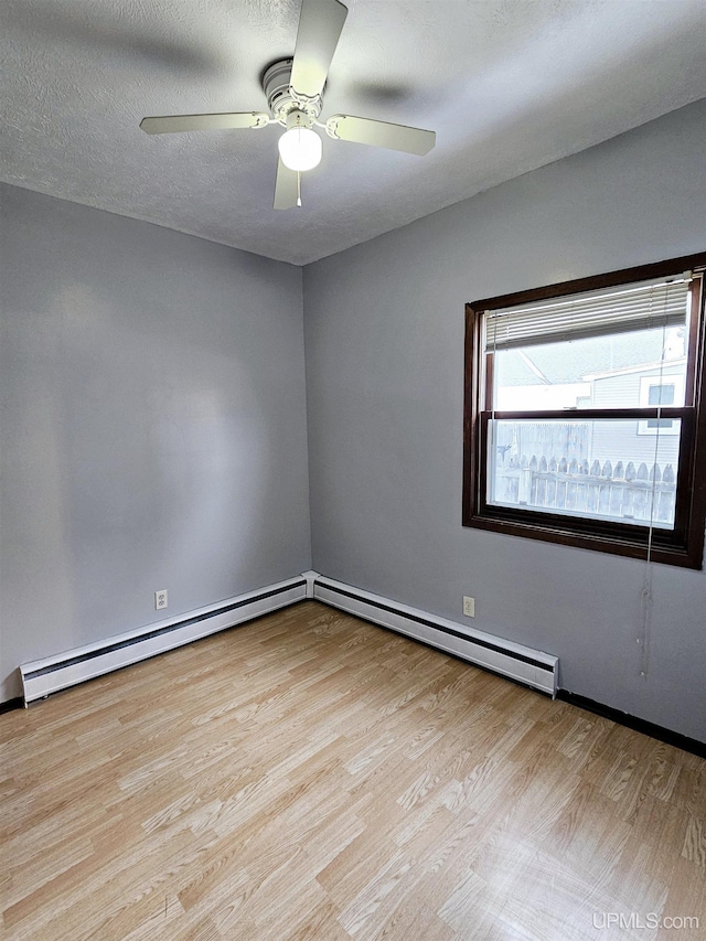 empty room with ceiling fan, a textured ceiling, a baseboard heating unit, and light hardwood / wood-style flooring