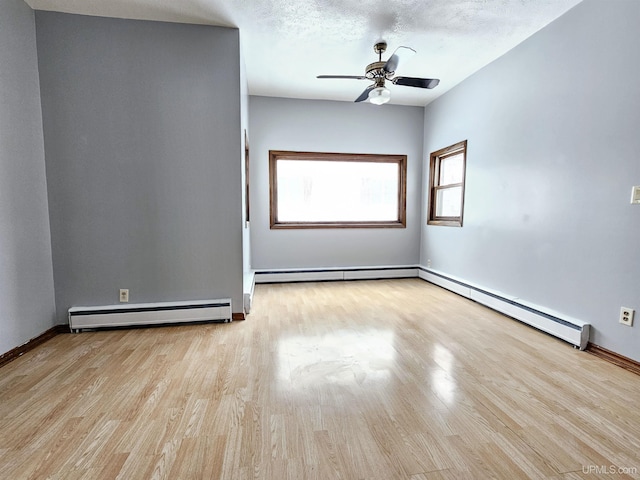 empty room featuring a textured ceiling, baseboard heating, and light wood-type flooring