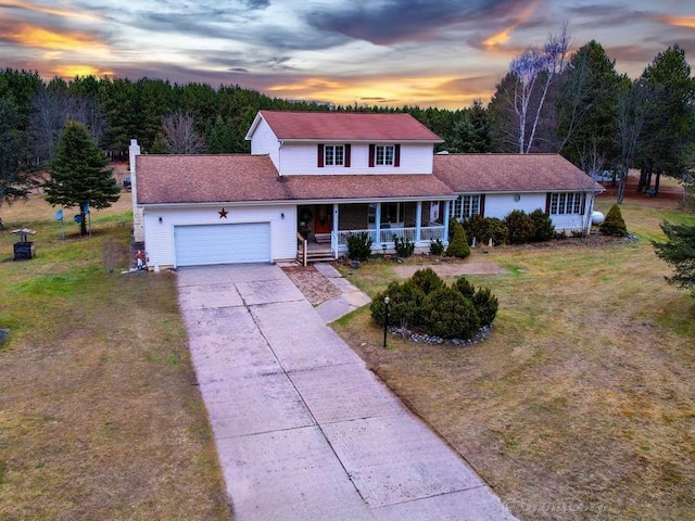 view of front of home with a garage, a lawn, and a porch