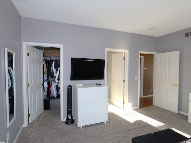 unfurnished bedroom featuring light carpet, a closet, and a spacious closet