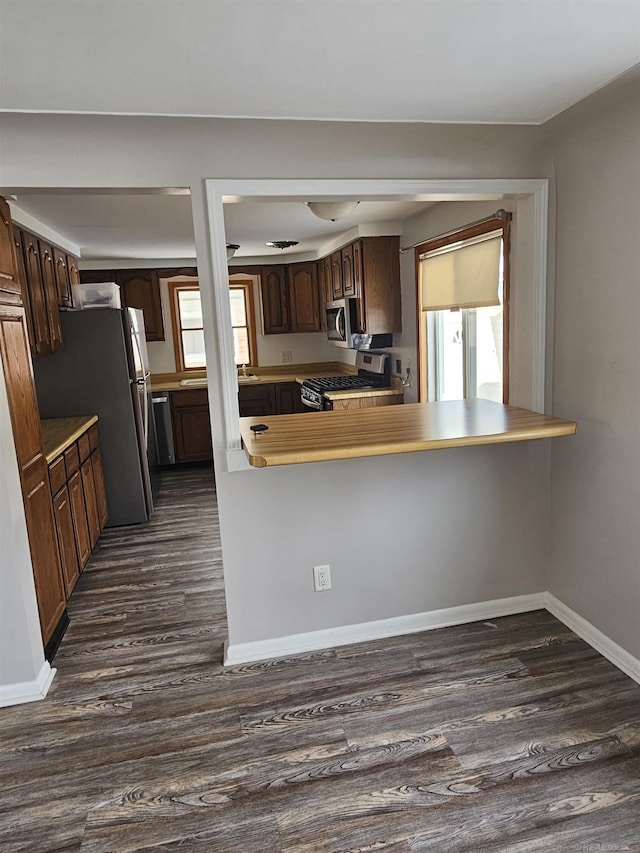 kitchen featuring stainless steel appliances, dark hardwood / wood-style flooring, and kitchen peninsula