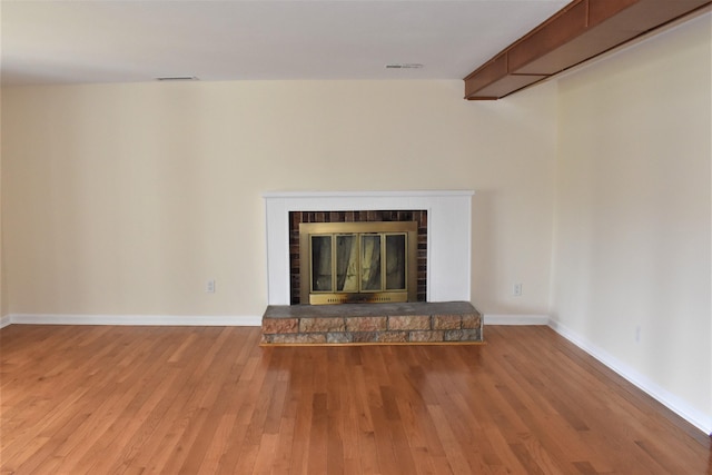 interior details featuring a brick fireplace, wood-type flooring, and beamed ceiling