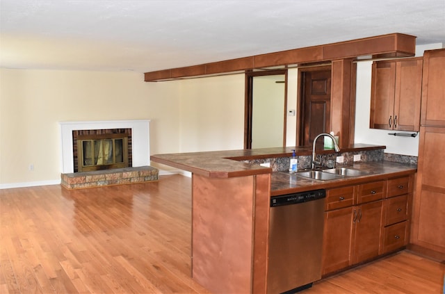 kitchen featuring kitchen peninsula, a brick fireplace, dishwasher, light hardwood / wood-style flooring, and sink