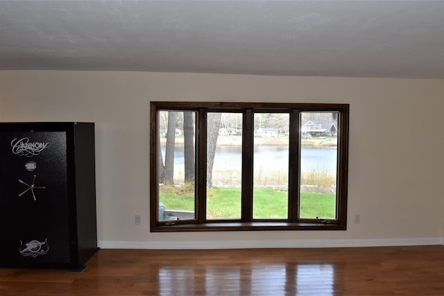 spare room featuring a water view and wood-type flooring