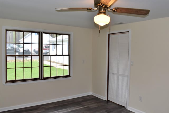 unfurnished bedroom featuring ceiling fan, dark hardwood / wood-style floors, and a closet