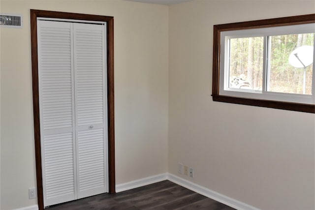 unfurnished bedroom with a closet and dark hardwood / wood-style flooring