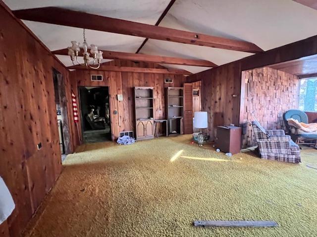 interior space with wood walls, an inviting chandelier, vaulted ceiling with beams, and carpet floors