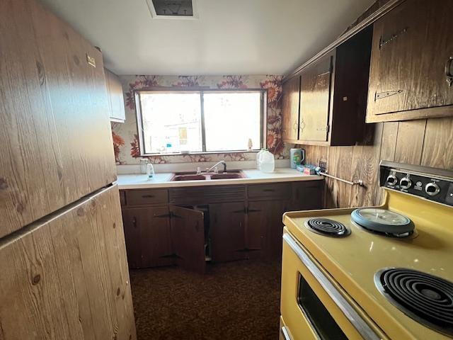 kitchen with sink, dark carpet, range, and refrigerator