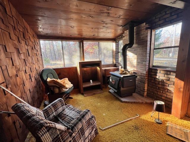 sunroom / solarium with lofted ceiling, a wood stove, and wooden ceiling