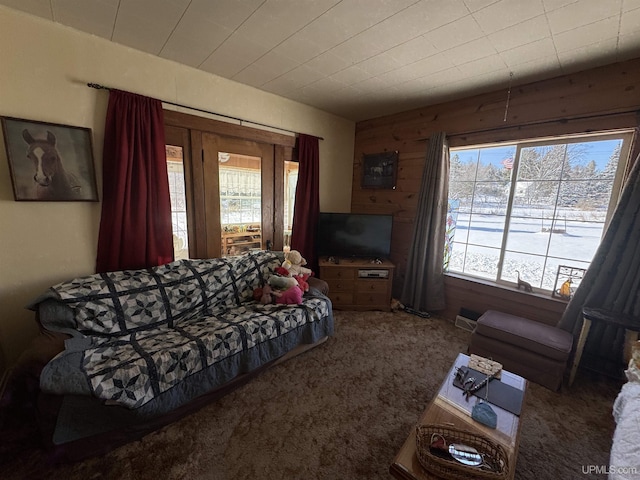 carpeted living room featuring wood walls